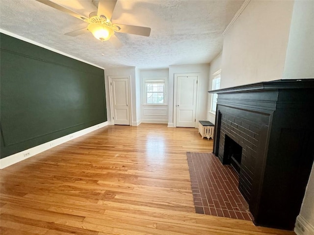 unfurnished living room with radiator, a textured ceiling, ceiling fan, light hardwood / wood-style flooring, and a fireplace