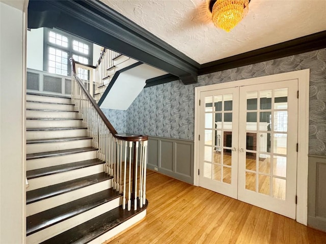 stairs with french doors, hardwood / wood-style floors, a textured ceiling, and ornamental molding