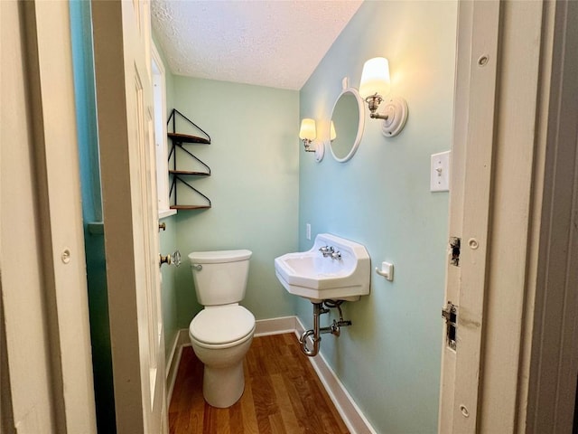 bathroom with sink, toilet, a textured ceiling, and hardwood / wood-style flooring