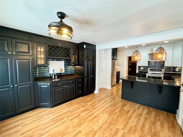 kitchen featuring sink, stainless steel appliances, decorative light fixtures, decorative backsplash, and a breakfast bar