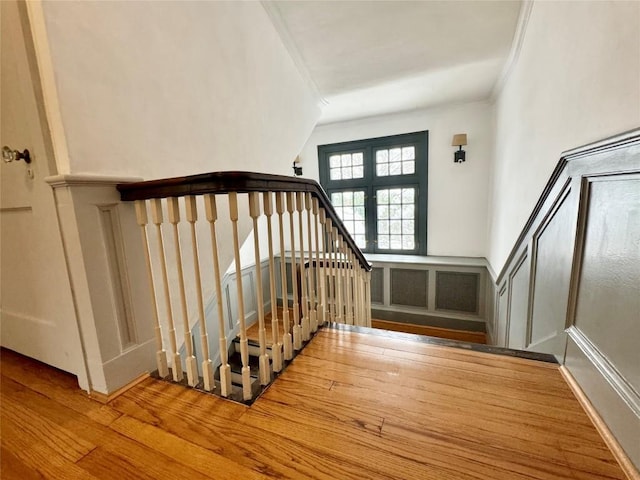 stairs with hardwood / wood-style floors and ornamental molding