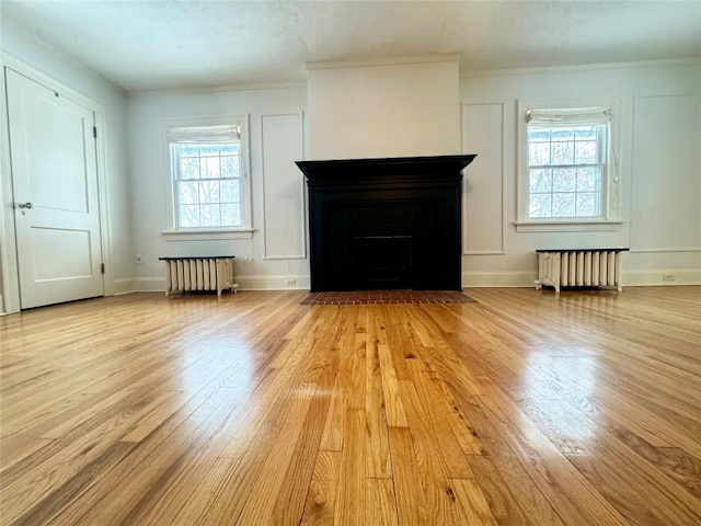 unfurnished living room featuring plenty of natural light, light wood-type flooring, and radiator heating unit