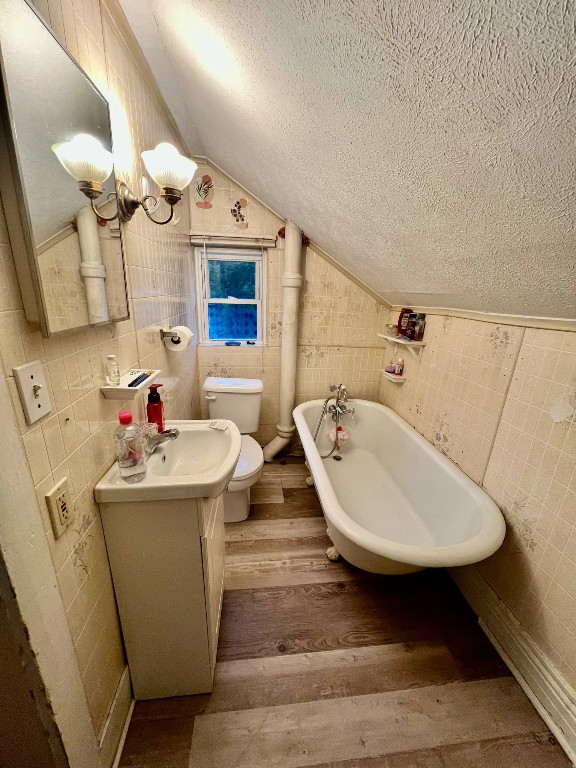 1121 E 27th St, Erie, PA 16504 - full bathroom with a textured ceiling, hardwood / wood-style flooring, tile walls, a freestanding tub, and vanity