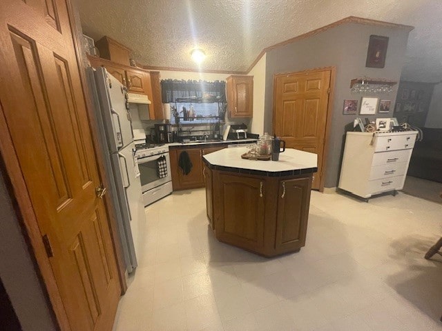 kitchen featuring white gas range, a textured ceiling, refrigerator, a kitchen island, and sink