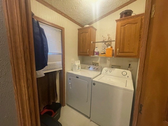 laundry area with washer and clothes dryer, a textured ceiling, crown molding, and cabinets