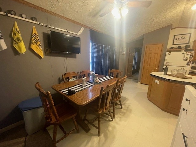 dining space with a textured ceiling, ceiling fan, and vaulted ceiling