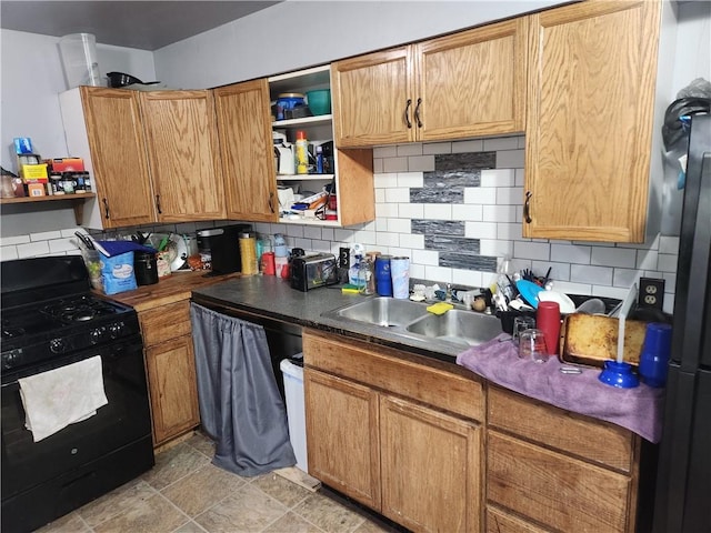 kitchen with tasteful backsplash, stainless steel refrigerator, sink, and black gas range oven