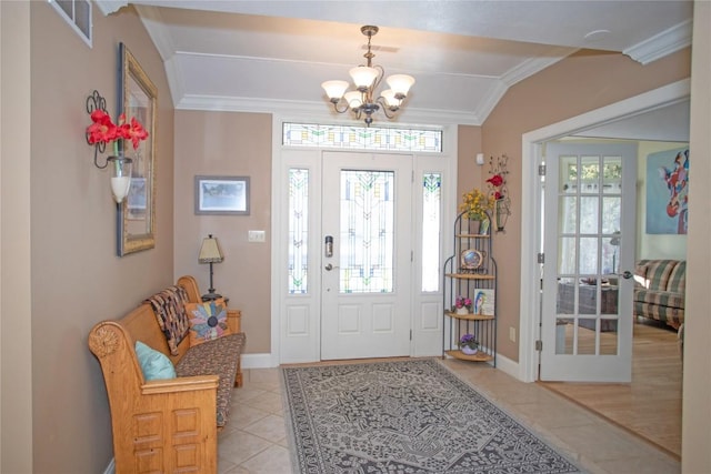 foyer entrance with a notable chandelier, light tile patterned flooring, and crown molding