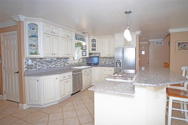 kitchen featuring light stone countertops, stainless steel appliances, a kitchen island, decorative light fixtures, and light tile patterned flooring