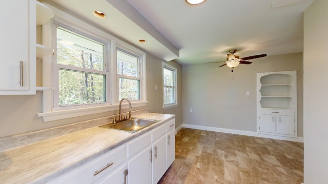 9170 Storey Rd, North East, PA 16428 - kitchen featuring a sink, white cabinetry, light countertops, ceiling fan, and baseboards