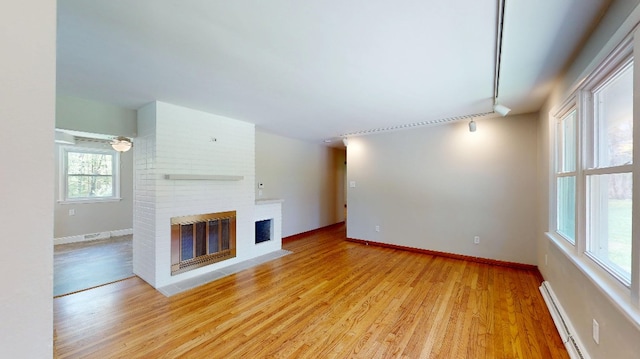 9170 Storey Rd, North East, PA 16428 - unfurnished living room featuring track lighting, a brick fireplace, light wood-style floors, a baseboard heating unit, and baseboards