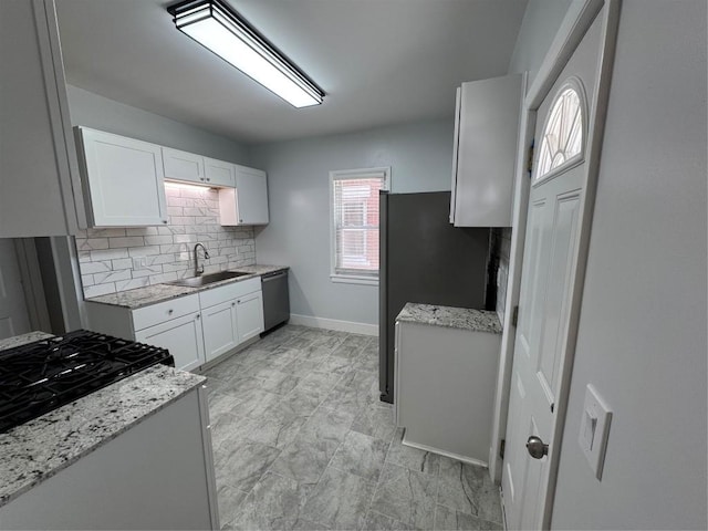 kitchen with stainless steel appliances, light stone countertops, white cabinets, backsplash, and sink