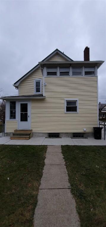 rear view of property featuring a lawn