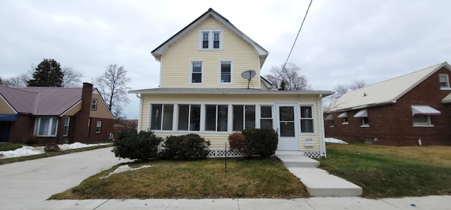 view of front of home with a front yard and a sunroom