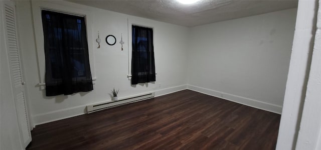 unfurnished room with baseboard heating, dark hardwood / wood-style flooring, and a textured ceiling