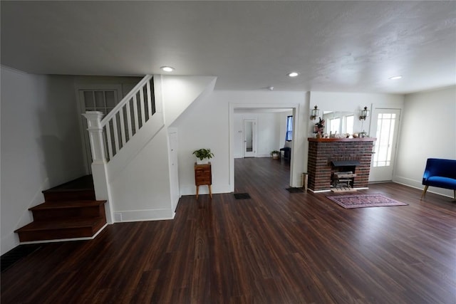 living room with dark hardwood / wood-style flooring and a brick fireplace