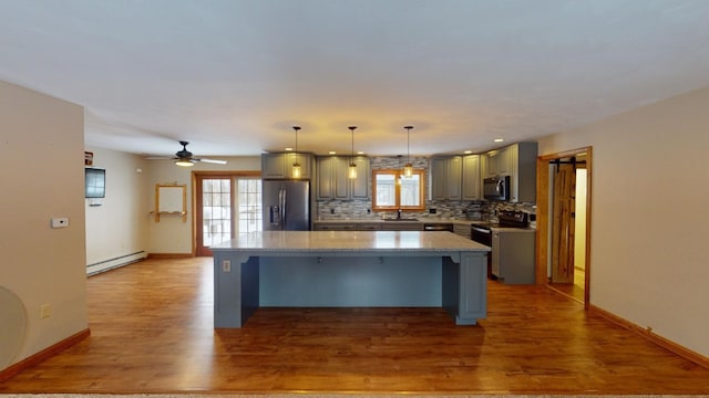 kitchen featuring backsplash, stainless steel appliances, sink, a baseboard radiator, and a center island