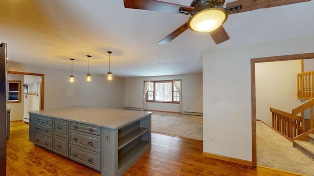 kitchen with gray cabinetry, ceiling fan, hanging light fixtures, a baseboard heating unit, and hardwood / wood-style floors