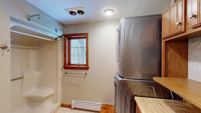 clothes washing area with stacked washer and clothes dryer and a baseboard heating unit