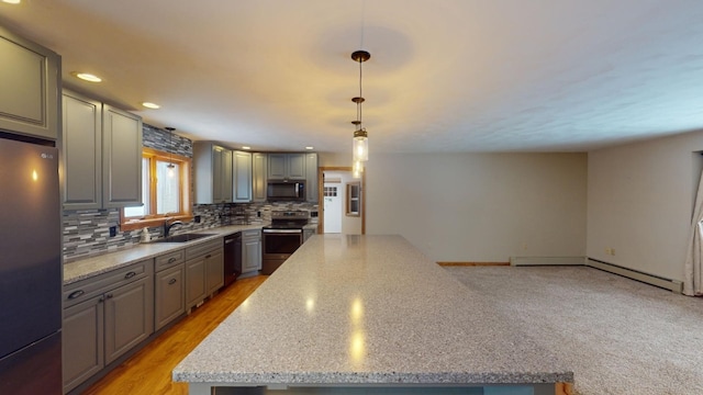 kitchen featuring a center island, appliances with stainless steel finishes, tasteful backsplash, decorative light fixtures, and light stone counters