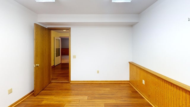 empty room featuring wooden walls and light hardwood / wood-style floors