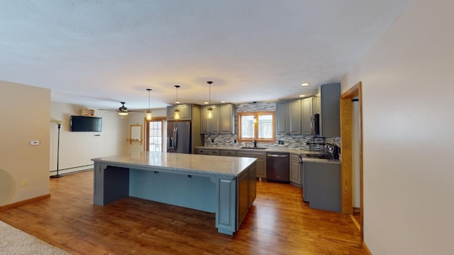 kitchen with decorative backsplash, stainless steel appliances, sink, decorative light fixtures, and a kitchen island