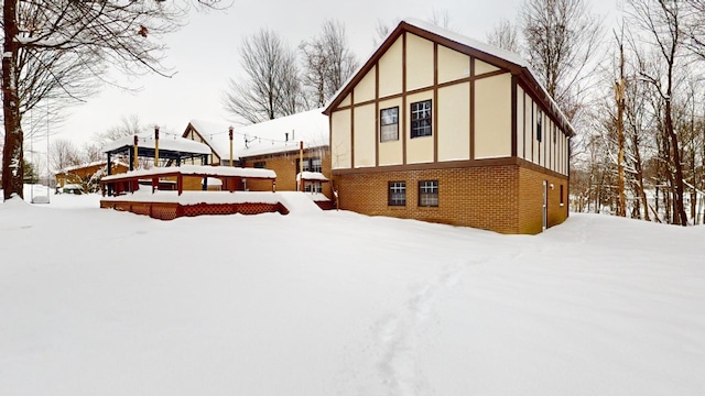 snow covered back of property featuring a deck