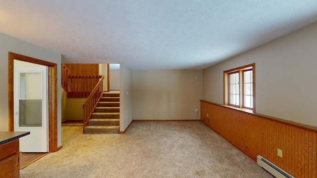 basement featuring light carpet, a textured ceiling, and baseboard heating