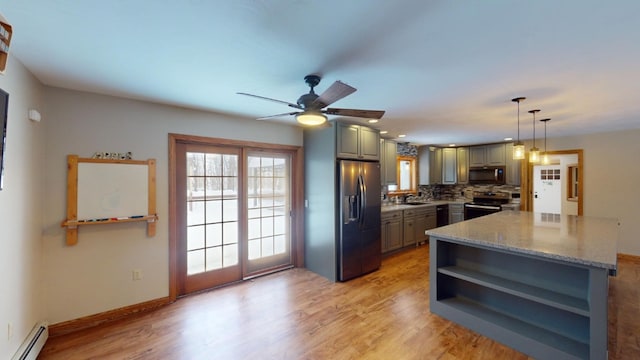 kitchen featuring light stone countertops, a baseboard heating unit, gray cabinets, decorative backsplash, and appliances with stainless steel finishes