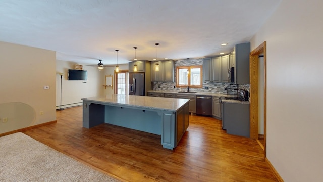 kitchen with hanging light fixtures, hardwood / wood-style flooring, tasteful backsplash, a kitchen island, and stainless steel appliances