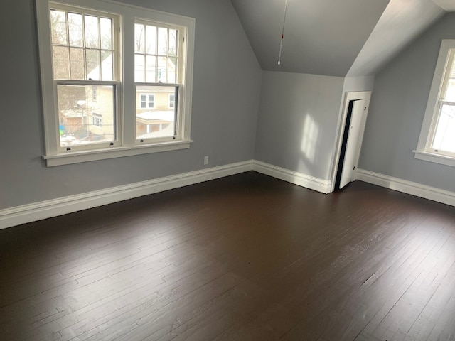 additional living space featuring vaulted ceiling and dark wood-type flooring