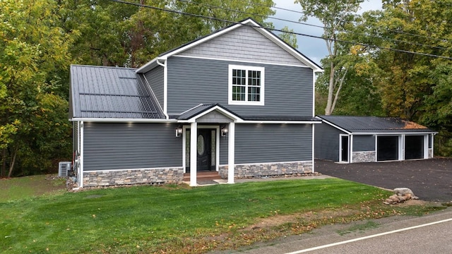 view of front property with an outbuilding, cooling unit, a front yard, and a garage