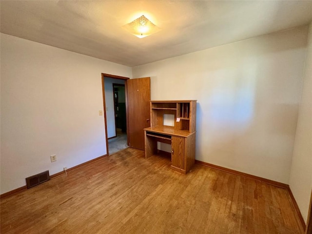 empty room with baseboards, visible vents, and light wood finished floors