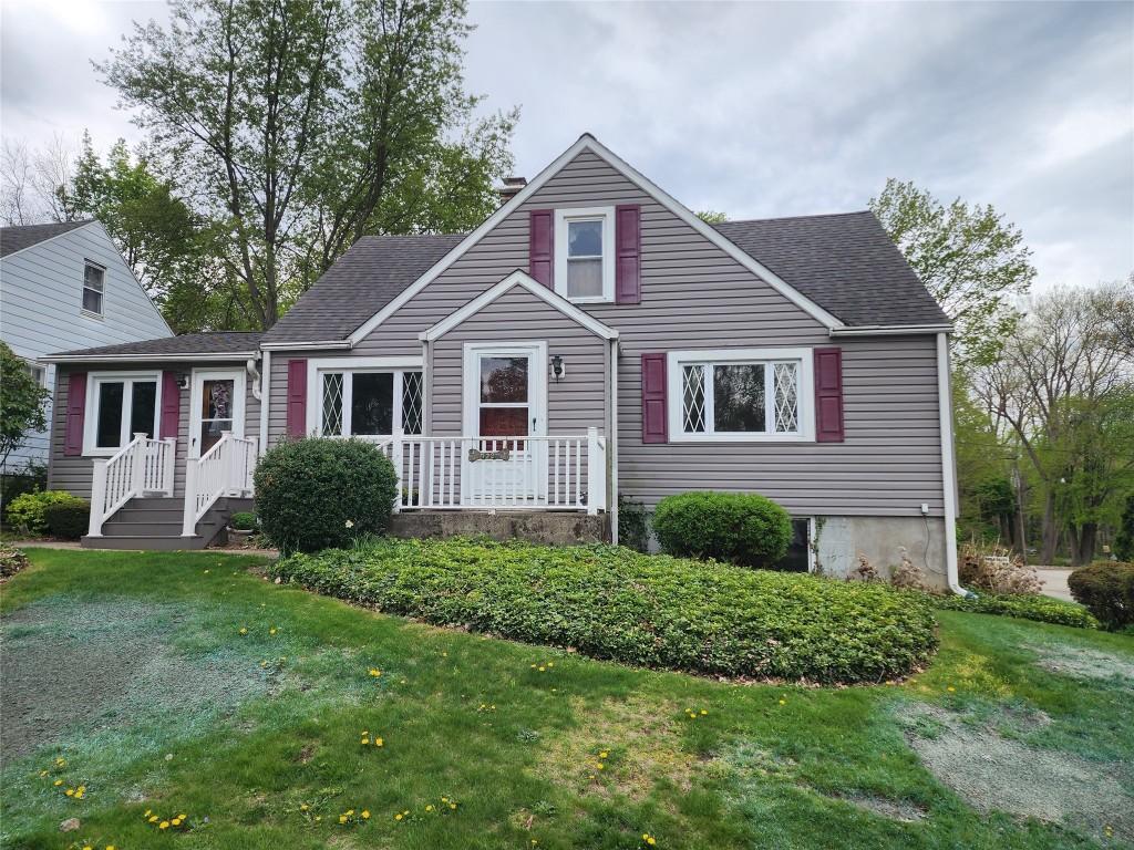 view of front of property with a shingled roof and a front lawn