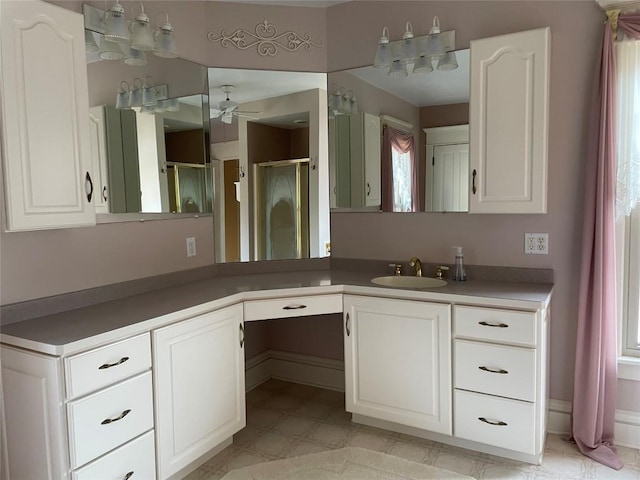 bathroom with ceiling fan, vanity, and a shower with door