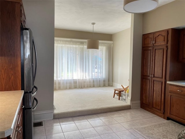 kitchen with hanging light fixtures, light carpet, and stainless steel fridge