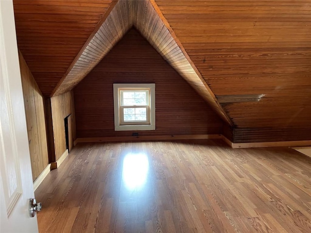 additional living space featuring hardwood / wood-style flooring, vaulted ceiling, wooden ceiling, and wooden walls