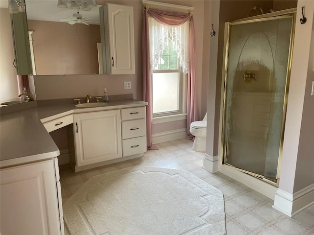 bathroom with vanity, a shower with door, toilet, and a healthy amount of sunlight