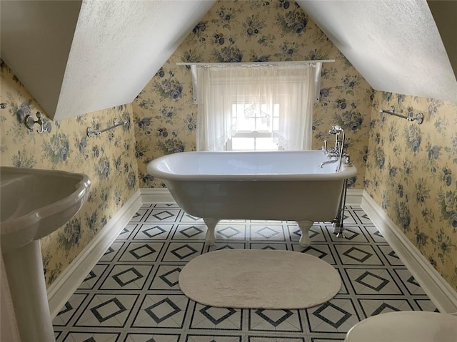 bathroom with vaulted ceiling, a tub, and a textured ceiling