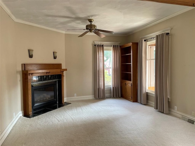 unfurnished living room with a premium fireplace, light colored carpet, ceiling fan, and crown molding