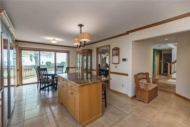 kitchen featuring a center island, dark stone countertops, crown molding, pendant lighting, and paneled built in fridge