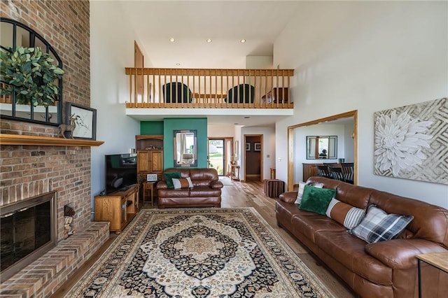 living room with a fireplace, a towering ceiling, and wood-type flooring