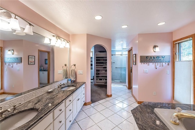 bathroom with tile patterned floors, vanity, walk in shower, and a textured ceiling