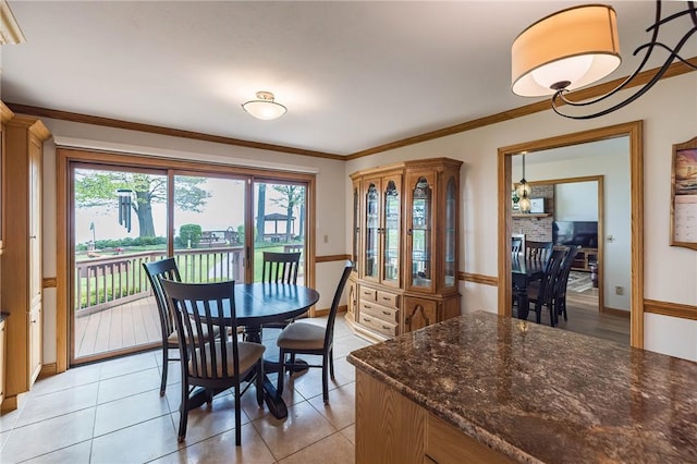 tiled dining space with a fireplace and crown molding