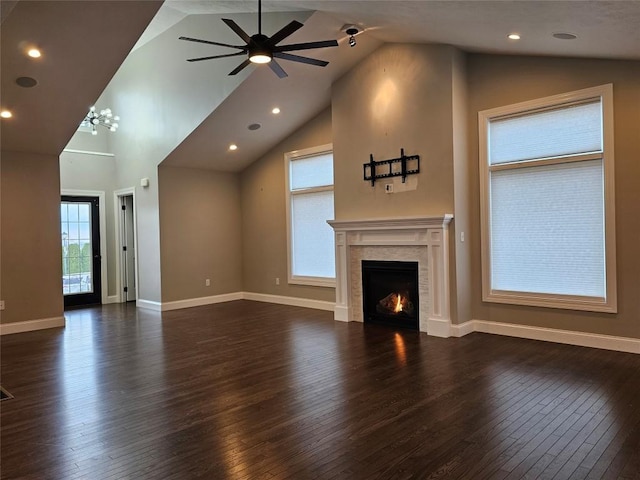 unfurnished living room with a tile fireplace, ceiling fan with notable chandelier, dark hardwood / wood-style floors, and high vaulted ceiling