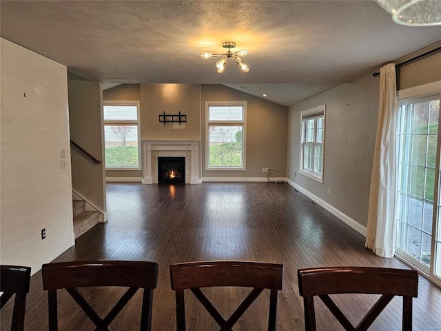 unfurnished living room with a textured ceiling, dark hardwood / wood-style flooring, plenty of natural light, and lofted ceiling