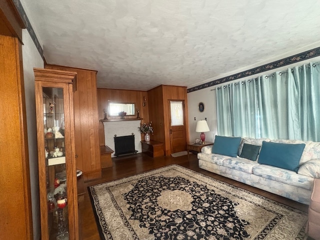 living room featuring wood finished floors, wooden walls, a textured ceiling, and a fireplace