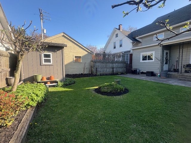 view of yard with fence, central AC unit, and a patio area