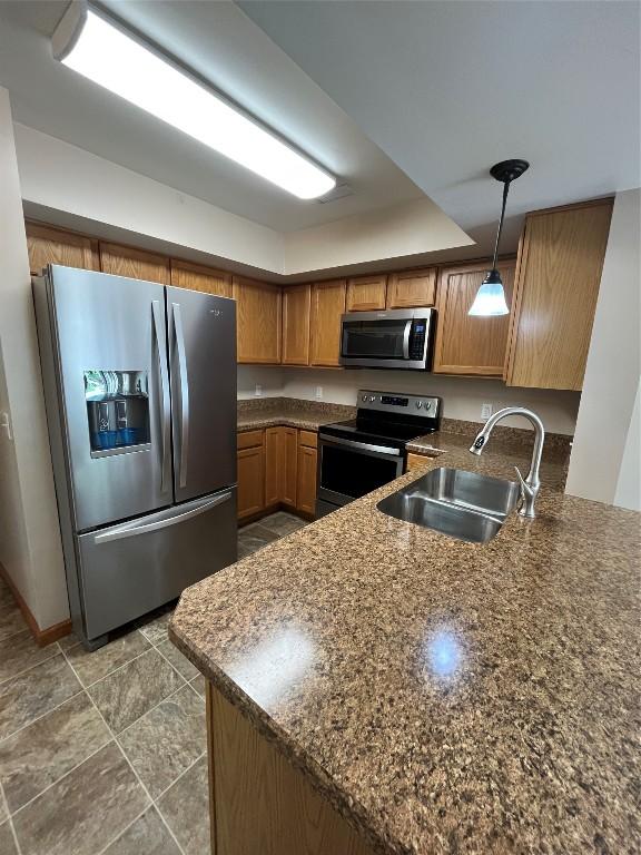 234 Walnut St Unit 13, Meadville, PA 16335 - kitchen with appliances with stainless steel finishes, a sink, brown cabinetry, pendant lighting, and a peninsula