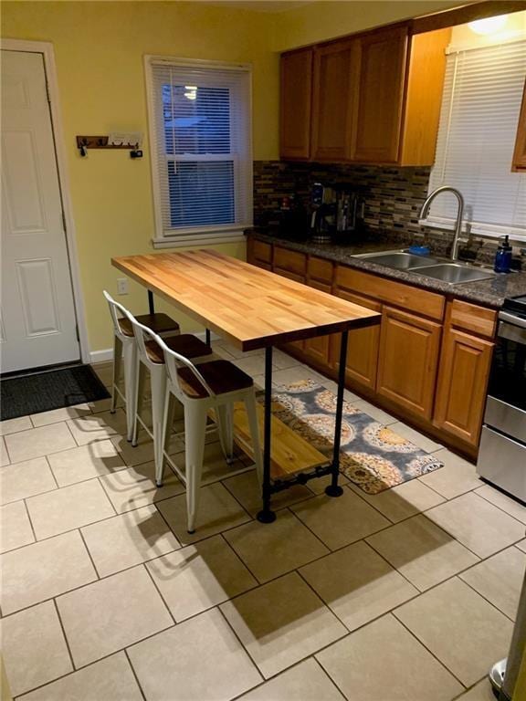 kitchen featuring light tile patterned floors, brown cabinets, a sink, and decorative backsplash